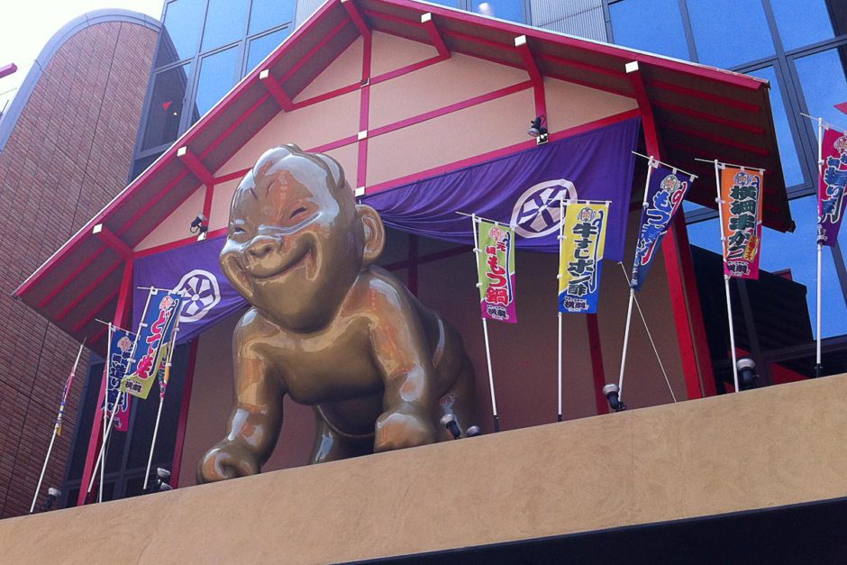 Billiken peers out onto the pedestrians from a building near Tsūtenkaku.