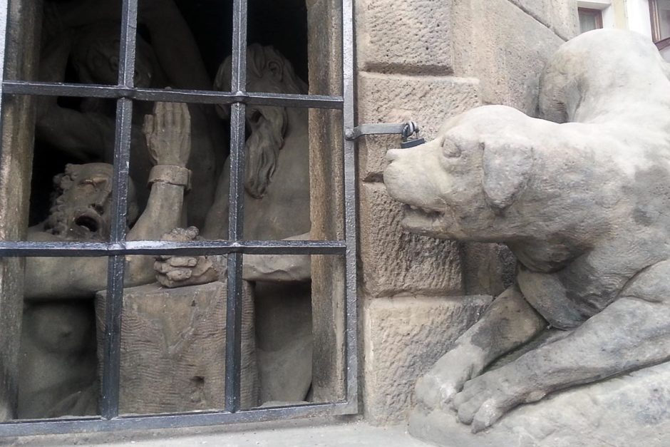 Statue of three figures in a kind of iron cage; detail of one of the statues on Charles Bridge.