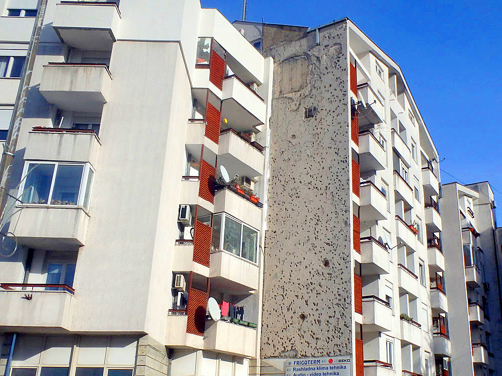 This apartment building was mostly rebuilt smoothly, except this one wall which is still covered in bullet holes.