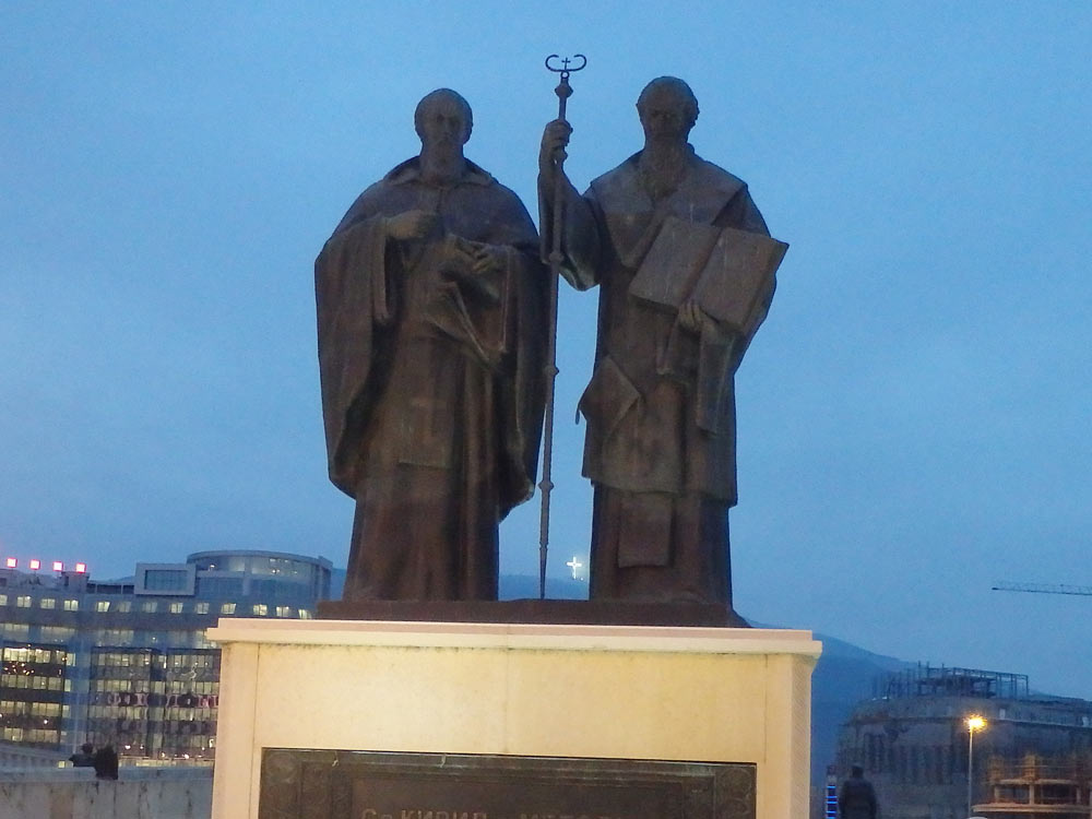 Religious statues with a large lit cross on the hill in the background