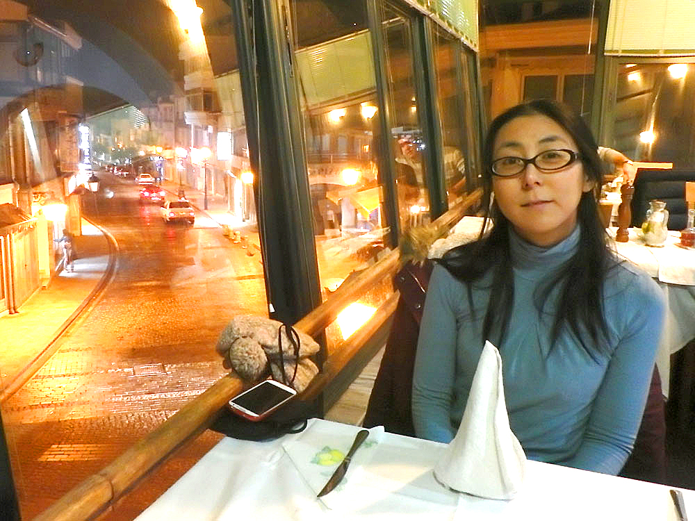 Masayo at Bazar restaurant for dinner, with the road through town below her