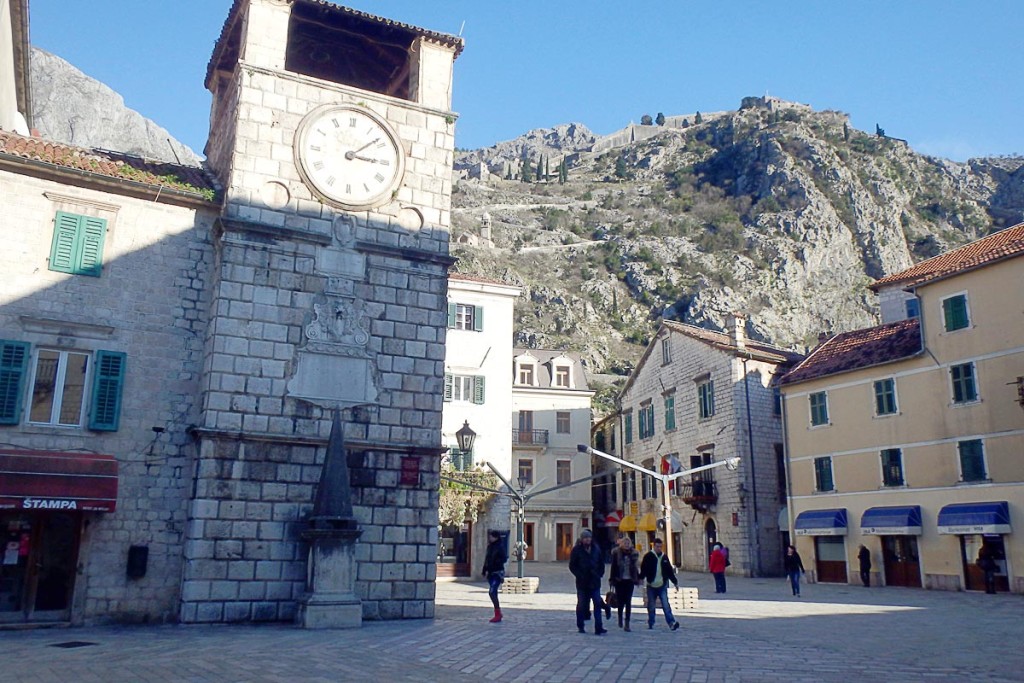 Ancient clock tower with fortress ruins on the hill behind.