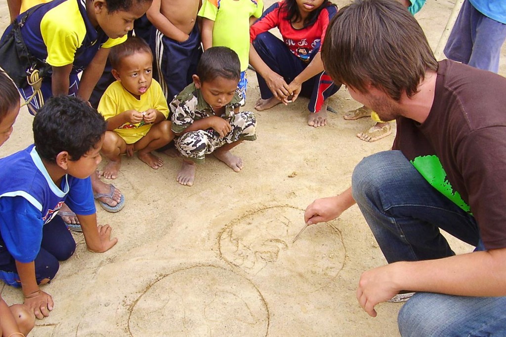 Nicholas draws the globe to show the Orang Asli kids where he was from.