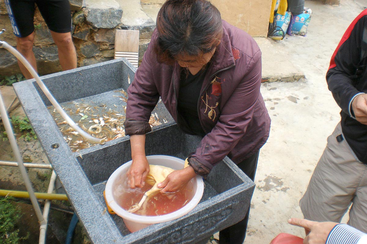 woman-plucking-chicken-lunch-fujian-tulou-china