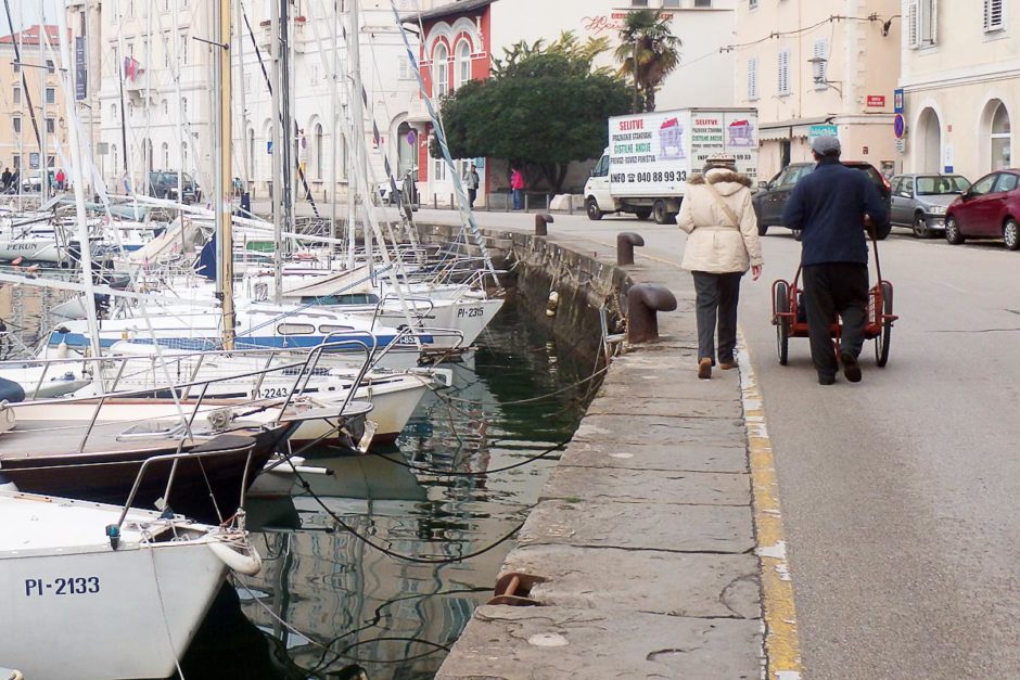 couple-with-cart-seaside-boats-piran